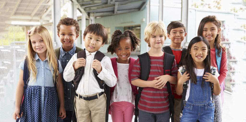 Young students at school standing with smiles wearing backpacks